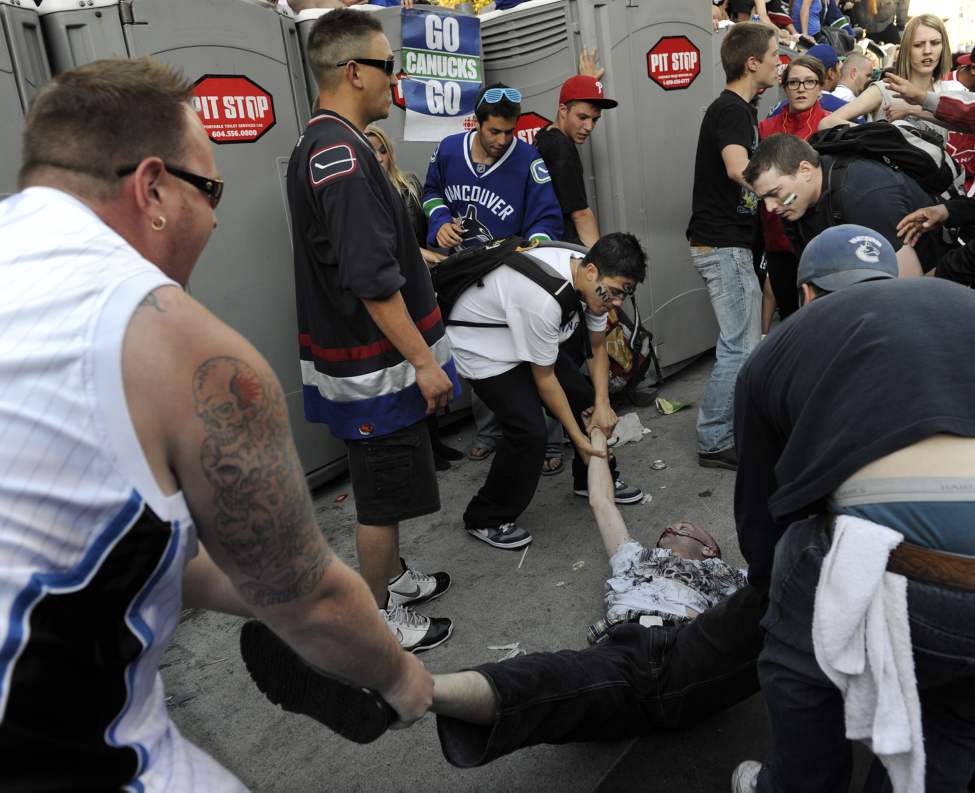 Fans remove an unconscious man injured in a fight amid rioting after the Vancouver Canucks lose to the Boston Bruins in the 2011 Stanley Cup final in Vancouver, British Columbia, Canada, on Wednesday, June 15, 2011. (Gerry Kahrmann/PNG/Postmedia News/MCT)
