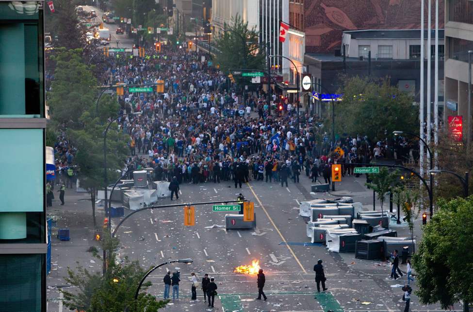 Police officers hold back the crowd after rioters burned police cars after the Vancouver Canucks were defeated by the Boston Bruins in the NHL's Stanley Cup Final in Vancouver, B.C., on Wednesday June 15, 2011. THE CANADIAN PRESS/Darryl Dyck