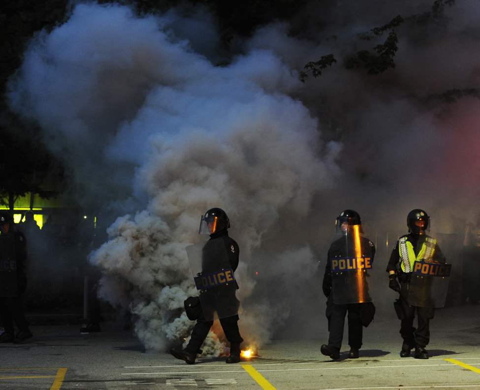 Riot police walk through smoke grenades after a rioting crowd torched two police cars, Vancouver, June 15 2011. Fans rioted after the Vancouver Canucks lost to the Boston Bruins in The Stanley cup final (Gerry Kahrmann / PNG staff photo)