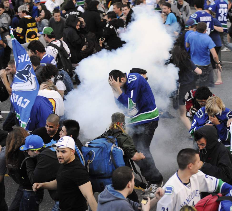 Canucks fans move along W. Georgia as police discharge flash bangs into the crowd after the reading of the riot act, Vancouver, June 15 2011. Fans riot after the Vancouver Canucks lost to the Boston Bruins in The Stanley cup final (Gerry Kahrmann / PNG staff photo)