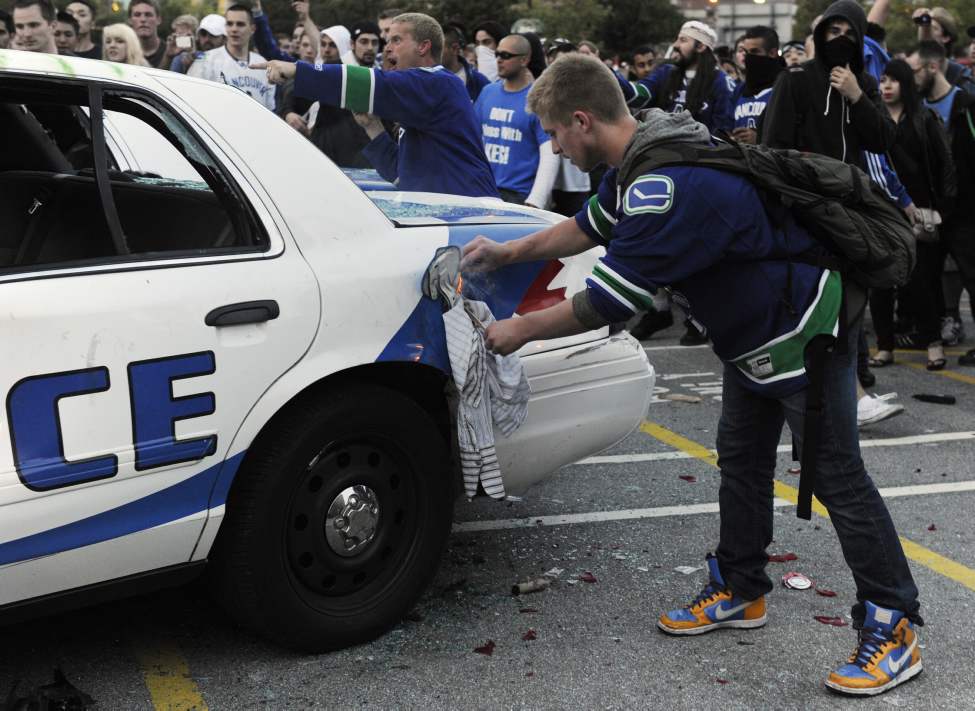 A Canucks fan works to light a police car on fire after a crowd trashed two cars after the Vancouver Canucks lost to the Boston Bruins in The Stanley cup final, Vancouver, June 15 2011. (Gerry Kahrmann / PNG staff photo)