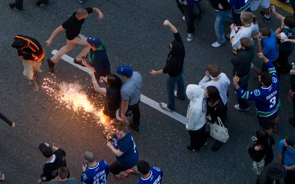 Revellers retreat as a police flash bang goes off after the Vancouver Canucks were defeated by the Boston Bruins in the NHL's Stanley Cup Final in Vancouver, B.C., on Wednesday June 15, 2011. THE CANADIAN PRESS/Darryl Dyck