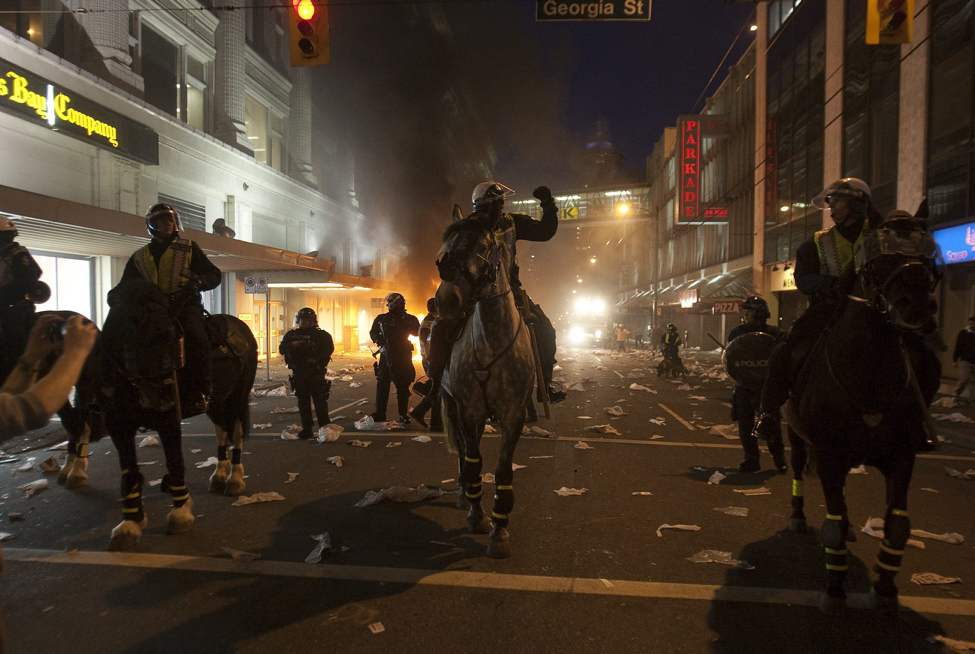 Police on horseback move down a street during a riot in downtown Vancouver, Wednesday, June 15, 2011 following the Vancouver Canucks 4-0 loss to the Boston Bruins in game 7 of the Stanley Cup hockey final. THE CANADIAN PRESS/Ryan Remiorz