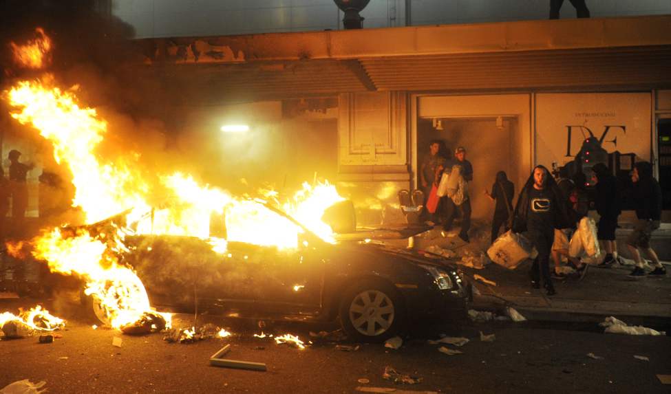 Looters leave the smashed display windows of the Bay past burning cars along Seymour north of Georgia after the Canucks lost game seven of the 2011 NHL Stanley Cup final Wednesday June 15, 2011 in Vancouver, B.C. (Ian Lindsay / PNG staff photo)