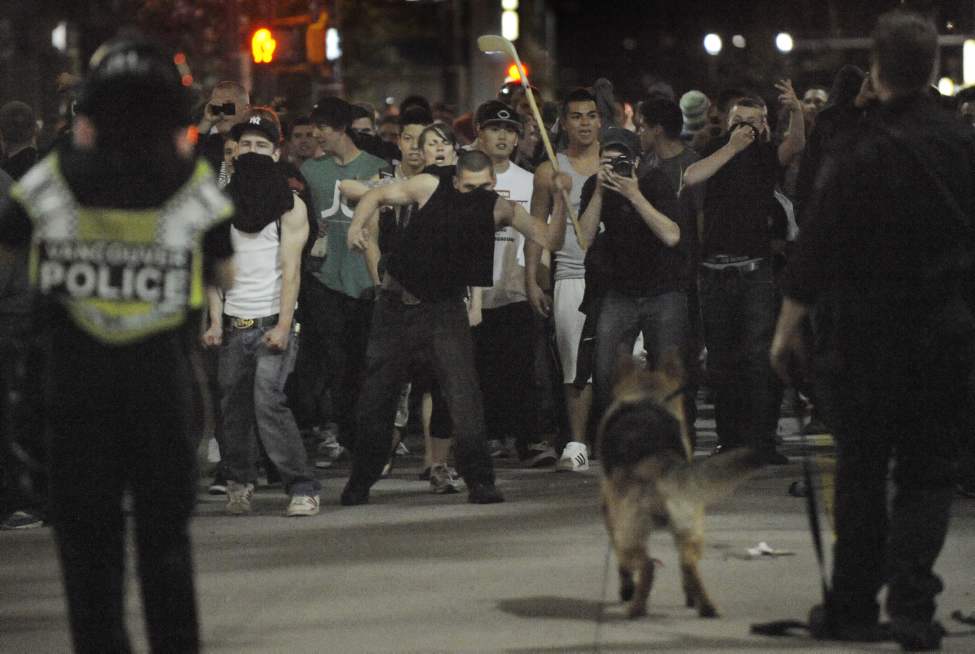 A man taunts a Police dog as Vancouver Canucks fans riot after their team lost to the Boston Bruins in NHL Stanley Cup final in Vancouver , B.C. June 15, 2011. (Arlen Redekop photo/ PNG)