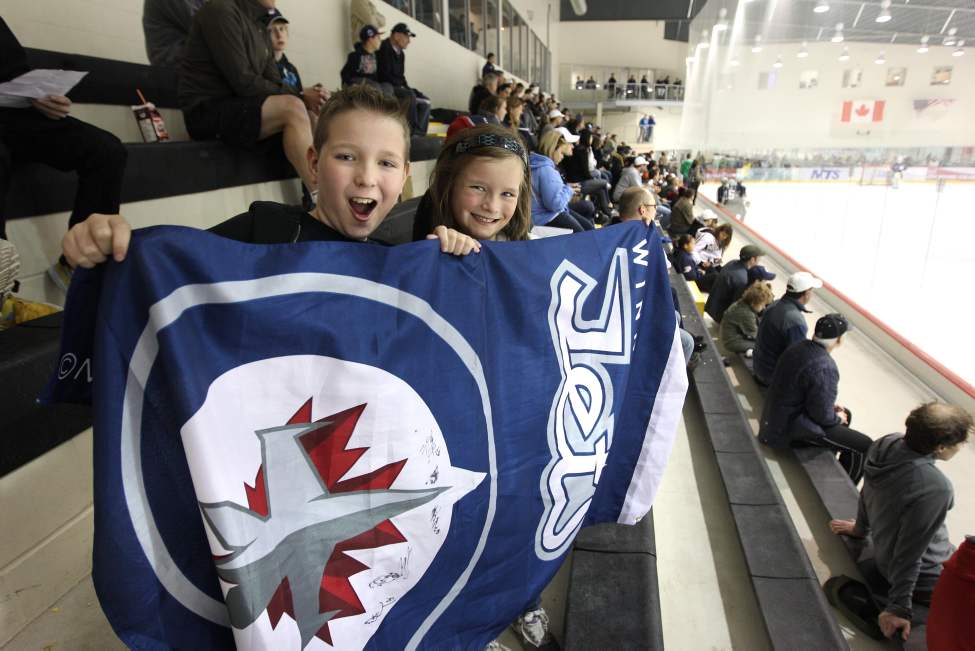 RUTH BONNEVILLE / WINNIPEG FREE PRESS
Brendan Hrushka, 12, and his sister Claire, 9, hold up their flag as they cheer on the Group C team as they practice on the ice.