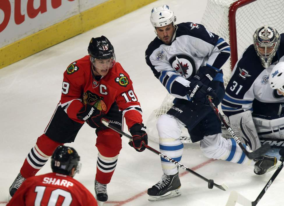 Winnipeg Jets Zach Bogosian, right, tries to get at the puck as Chicago Blackhawks superstar Johnathan Toews comes around the net during third period. (Joe Bryksa / Winnipeg Free Press)