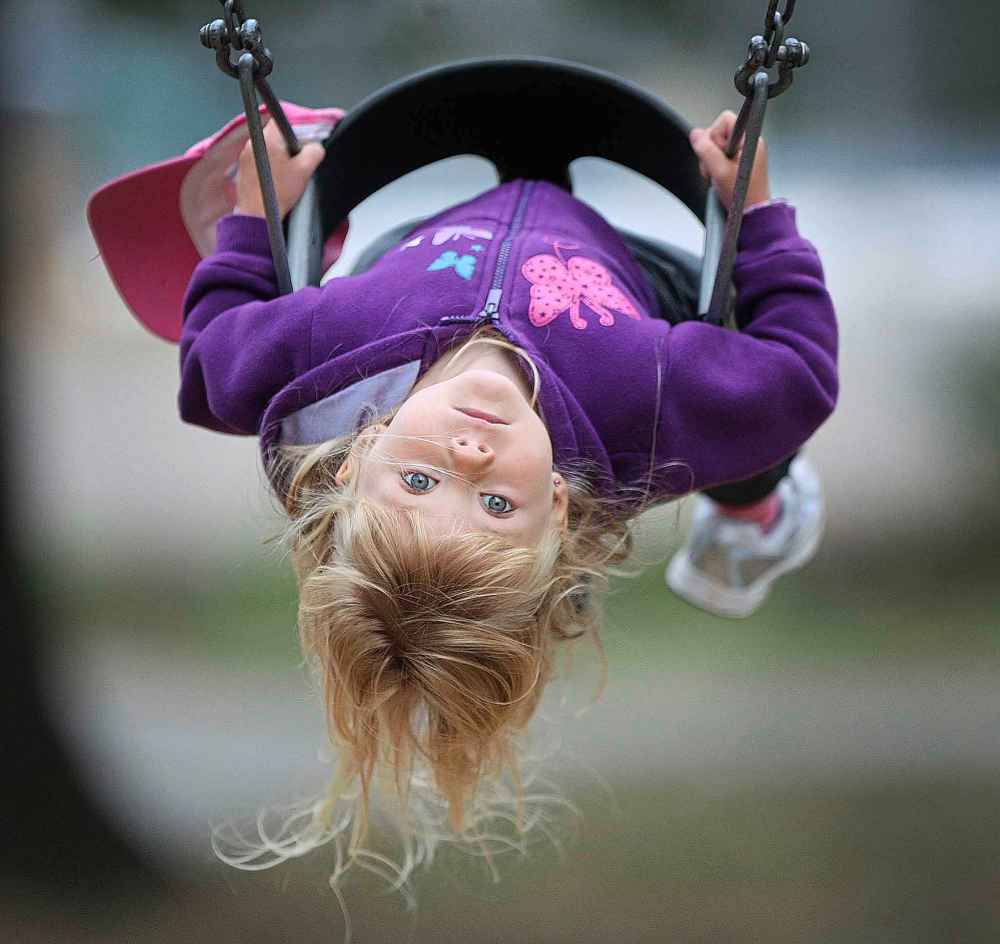 3-year-old Eva Armstrong keeps on eye on things while swinging with her dad and sibling in Kildonan Park in September 2012.