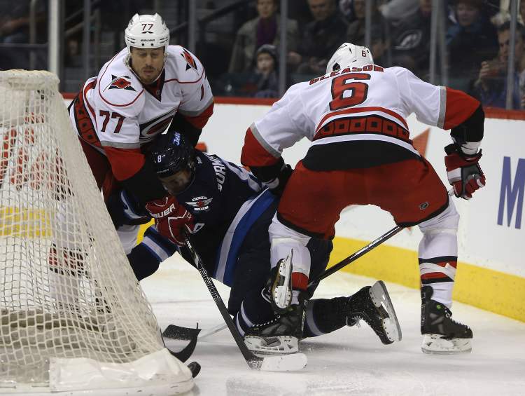 TREVOR HAGAN / WINNIPEG FREE PRESS
Winnipeg Jets' Alexander Burmistrov is hit between Carolina Hurricanes' Joe Corvo (77) and Tim Gleason (6) behind the Carolina net during the second period.