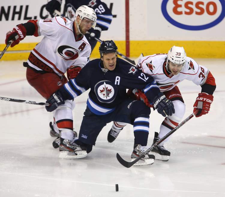 TREVOR HAGAN / WINNIPEG FREE PRESS
Winnipeg Jets' Olli Jokinen (12) tries to hold up Carolina Hurricanes' Jordan Staal (11) and Patrick Dwyer (39) during third-period action.