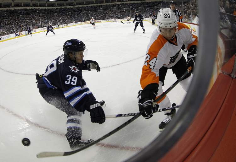 TREVOR HAGAN / WINNIPEG FREE PRESS
Winnipeg Jets' Tobias Enstrom (39) swats the puck away from Philadelphia Flyers' Matt Read (24) during first period action at the MTS Centre Saturday.