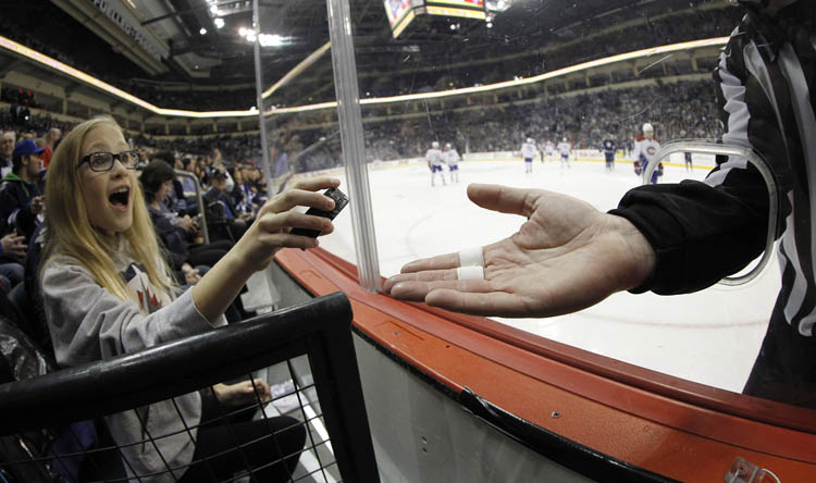 TREVOR HAGAN/WINNIPEG FREE PRESS
Linesman Brad Kovachik hands a game puck to Theresa Buchel, 10, during the first period of the Montreal Canadiens versus Winnipeg Jets game at MTS Centre on Thursday.