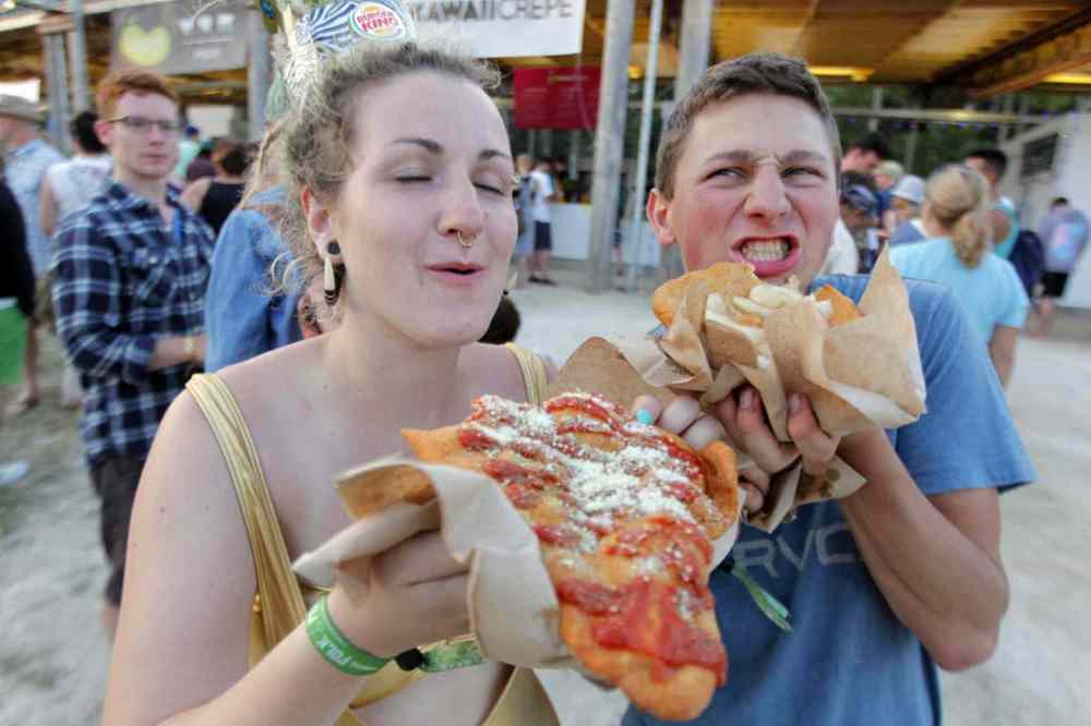 BORIS MINKEVICH / WINNIPEG FREE PRESS
Claire Waters and Danny Heinrichs gobble up some famous Whaletails at the festival eating area. The Winnipeggers say they expect to eat at least seven of them before the end of the weekend.
