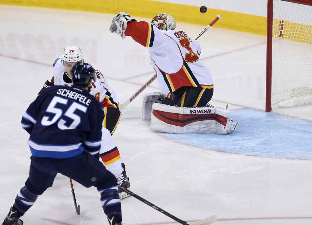 TREVOR HAGAN/WINNIPEG FREE PRESS
Winnipeg Jets' Drew Stafford (12) has his shot bounce off the head of Calgary Flames' Joni Ortio (37) before going in the net during NHL hockey action on Saturday.