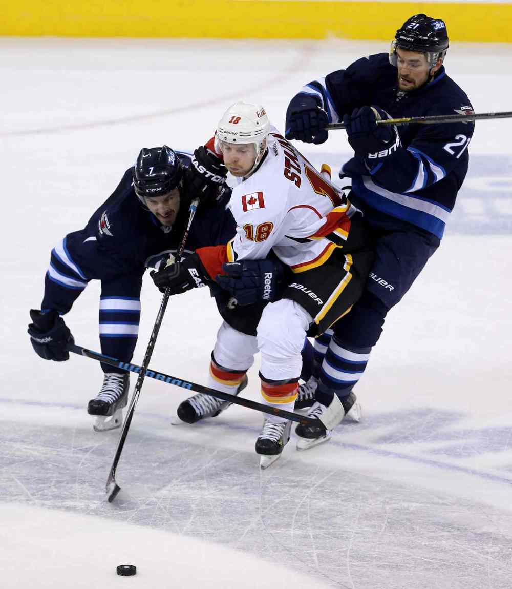 TREVOR HAGAN/WINNIPEG FREE PRESS
Winnipeg Jets' Keaton Ellerby (7) and TJ Galiardi (21) sandwich Calgary Flames' Matt Stajan (18) during NHL action on Saturday.