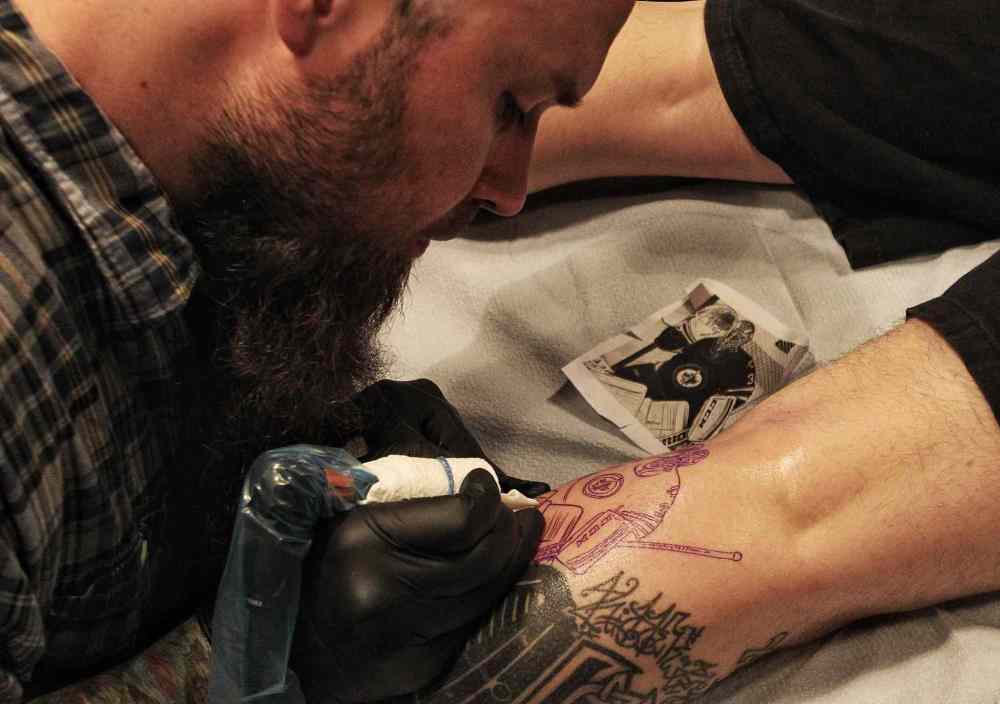 Mike Deal / Winnipeg Free Press
Chad Fabian gets a Winnipeg Jets tattoo applied to one of his calves Wednesday night by artist Dave Nazgul at 13th Hour Tattoo.