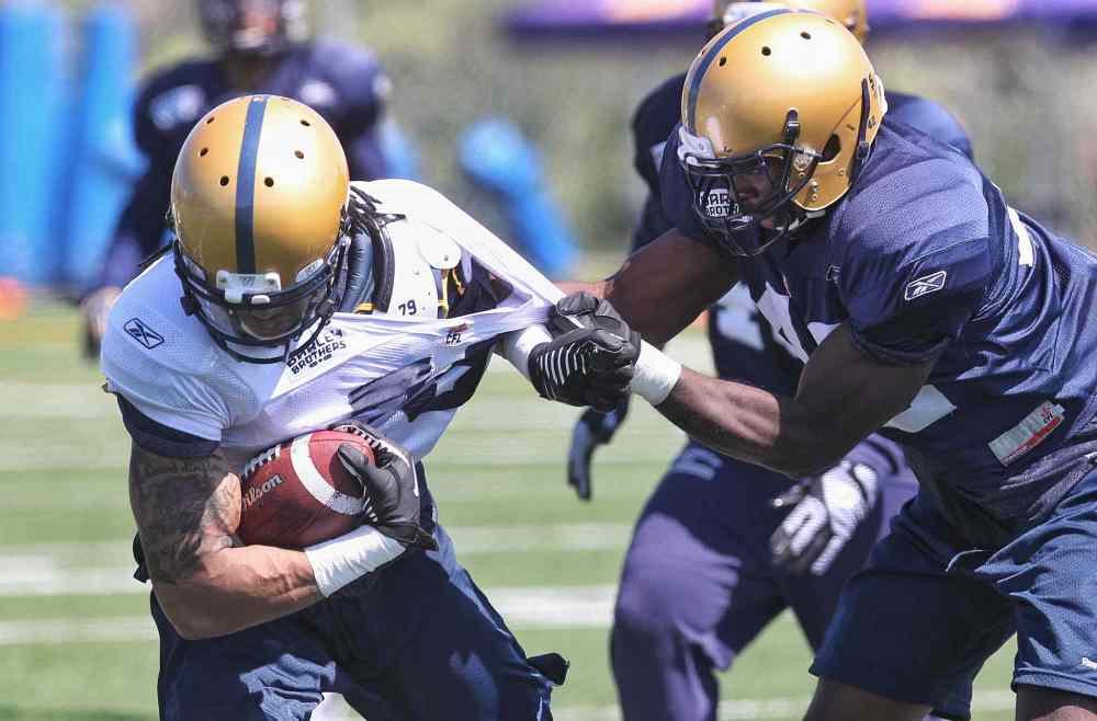 Mike Deal / Winnipeg Free Press
Greg Childs (79) is pulled down by Curtis Taylor (42) during the first day of the Winnipeg Blue Bombers training camp Sunday. 150531 May 31, 2015 Mike Deal / Winnipeg Free Press