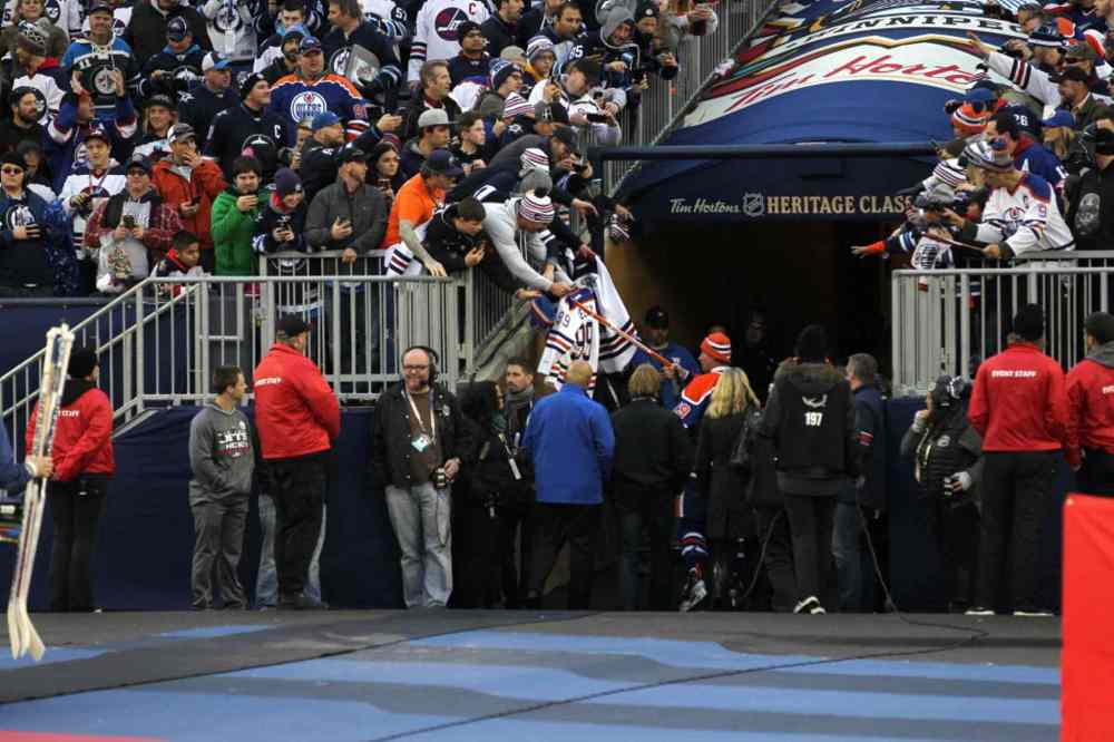 RUTH BONNEVILLE / WINNIPEG FREE PRESS
A Wayne Gretzky fan holds out a jersey with both the Winnipeg Jets colours and Edmonton Oilers colours on it to give to him as he walks off the field. But Gretzky doesn't take jersey, only hands the fan his stick as he walks off.
