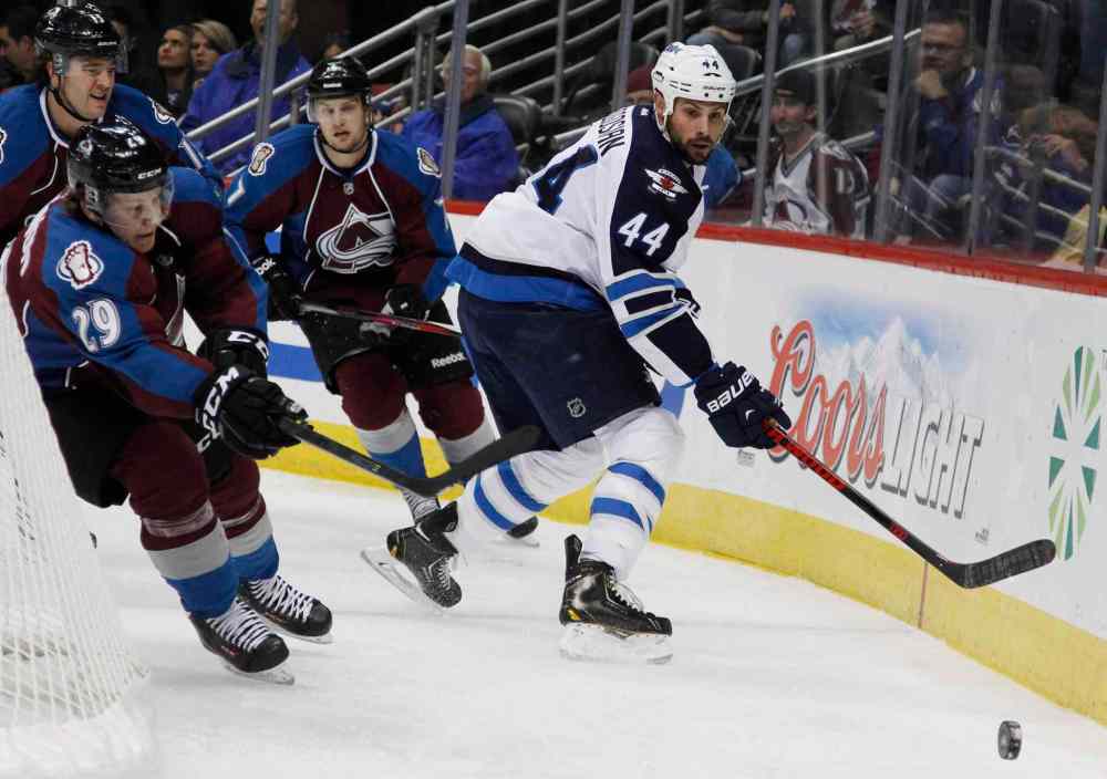 David Zalubowski / The Associated Press
Winnipeg Jets defenseman Zach Bogosian (right) clears the puck from behind the net as Nathan MacKinnon (left) and John Mitchell give chase during the second period.