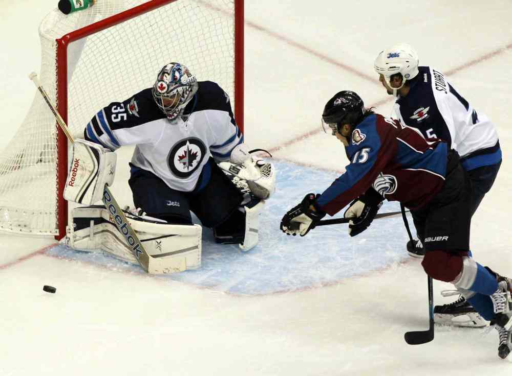 David Zalubowski / The Associated Press
Winnipeg Jets goalie Al Montoya makes a stick save off a shot by Colorado Avalanche winger PA Parenteau (centre) as Jets defenceman Mark Stuart backchecks during the third period.