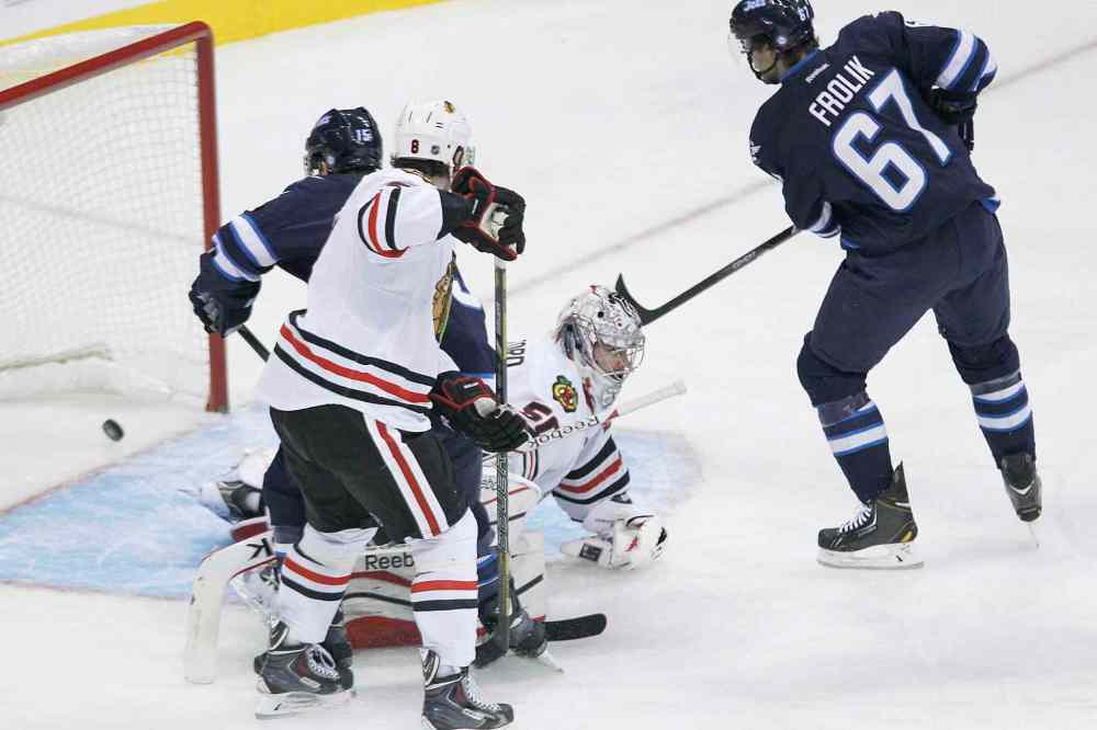 John Woods / The Canadian Press
Chicago Blackhawks' goaltender Corey Crawford (bottom) can't stop a shot from the point by Winnipeg Jets defenceman Toby Enstrom as Matt Halishchuk (15) and Michael Frolik (67) of the Jets and Hawks' Nick Leddy (8) look for the rebound during the first period.