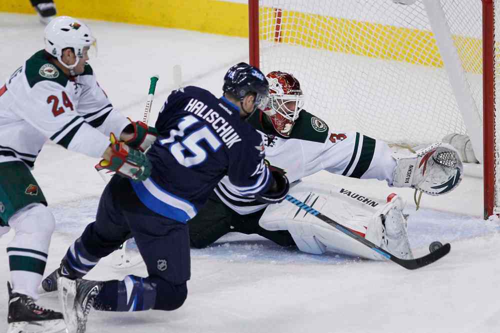 JOHN WOODS / THE CANADIAN PRESS
Winnipeg Jets forward Matt Halischuk scores puts the puck past Minnesota Wild goaltender Niklas Backstrom as the Wild's Matt Cooke (24) attempts to push him off the puck during the third period.