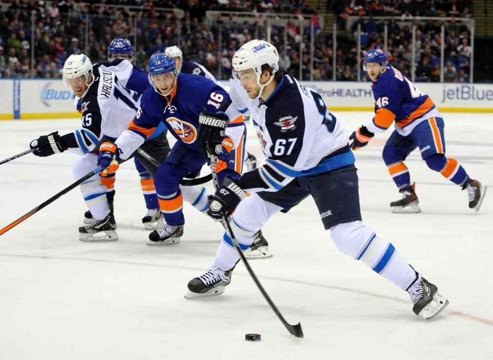 Kathy Kmonicek / The Associated Press
Winnipeg Jets forward Michael Frolik (67) takes a shot on goal as Peter Regin (16) of the New York Islanders in the first period.