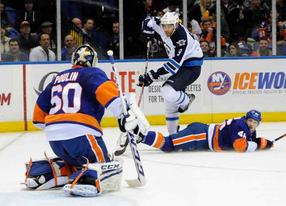 Kathy Kmonicek / The Associated Press
Winnipeg Jets' Evander Kane (centre) skips over a fallen New York Islanders' Matt Donovan (right) to take a shot on goal at goalie Kevin Poulin in the first period.