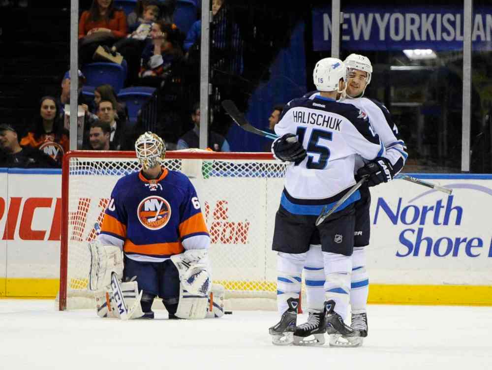 Kathy Kmonicek / The Associated Press
New York Islanders goalie Kevin Poulin (left) reacts as Winnipeg Jets forward Devin Setoguchi (right) celebrates his goal with Matt Halischuk in the second period.