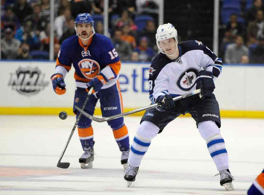 Kathy Kmonicek / The Associated Press
Winnipeg Jets defenceman Jacob Trouba (right) flicks the puck down the ice and away from New York Islanders forward Cal Clutterbuck in the third period.