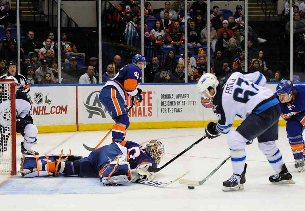 Kathy Kmonicek / The Associated Press
New York Islanders goalie Kevin Poulin (bottom) dives to block a shot on goal by Winnipeg Jets' Michael Frolik (67) as Matt Martin (right) defends from behind in the third period.