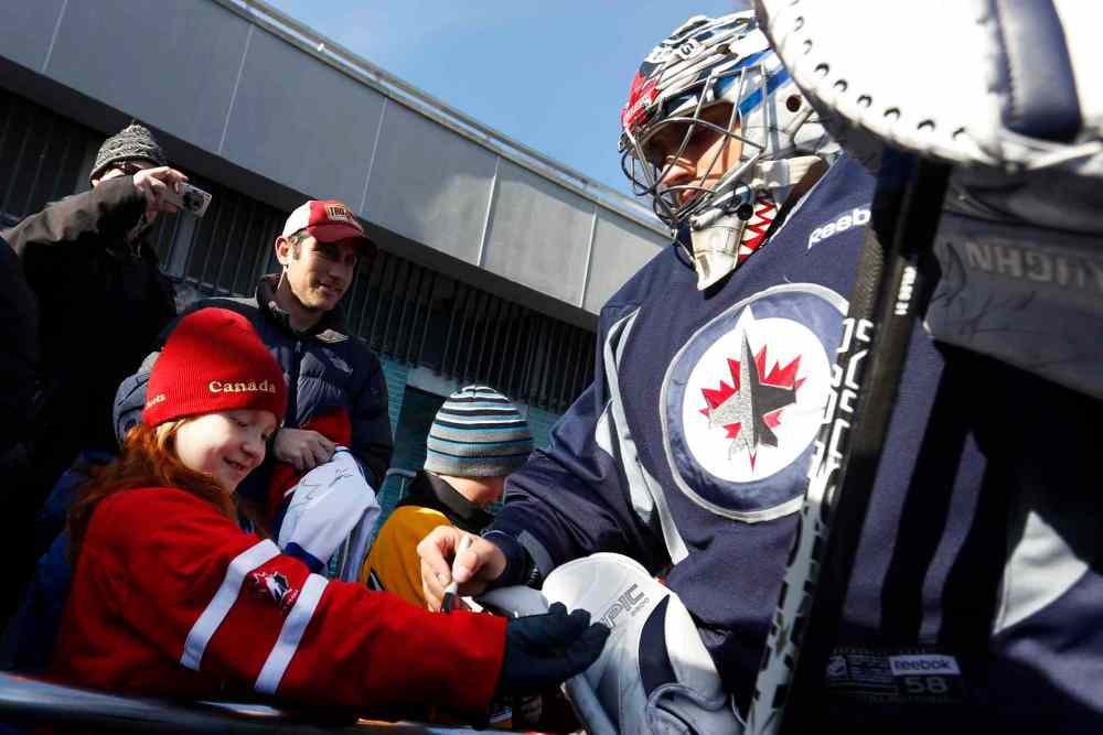 Jason DeCrow / The Associated Press
Winnipeg Jets goalie Ondrej Pavelec (right) signs an autograph for fan Alison Giebler, 8, of New York.