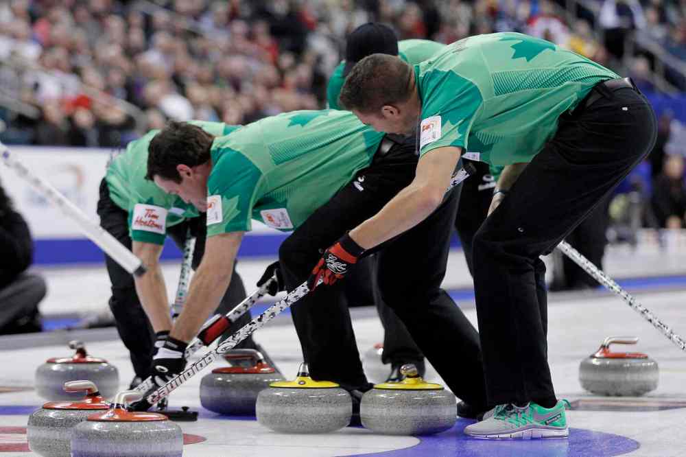 John Woods / The Canadian Press
Tyrel Griffith (left), Rick Sawatsky and John Morris (right) sweep one of John Cotter's stones to score two points in the fifth end.