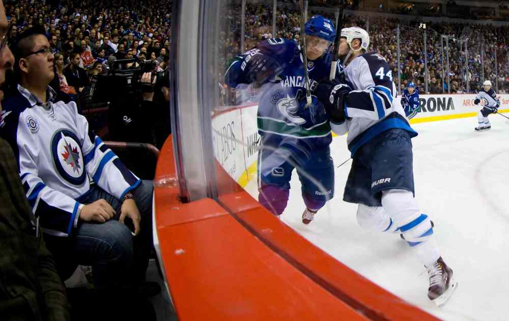 DARRYL DYCK / THE CANADIAN PRESS
Winnipeg Jets defenceman Zach Bogosian (right) checks Vancouver Canucks' Jannik Hansen into the boards during the first period.