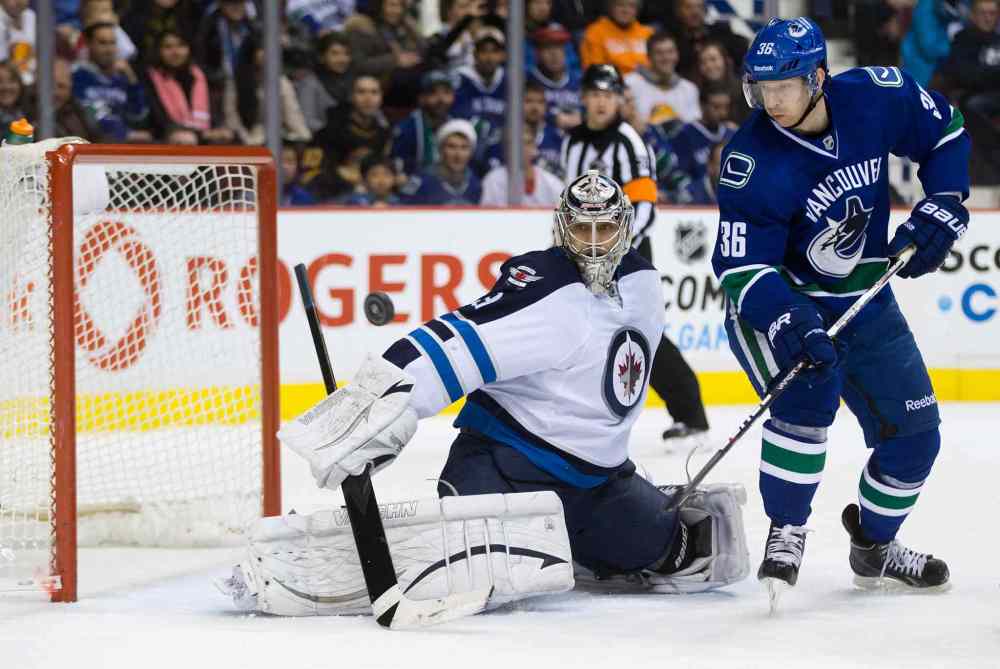 DARRYL DYCK / THE CANADIAN PRESS
Jannik Hansen (right) of the Vancouver Canucks tips the puck wide of Winnipeg Jets goalie Ondrej Pavelec.