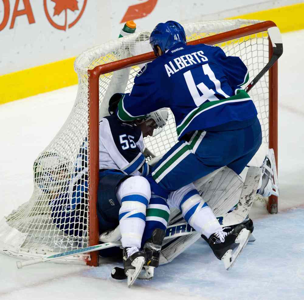 DARRYL DYCK / THE CANADIAN PRESS
Winnipeg Jets forward Mark Scheifele (centre) falls on Vancouver Canucks goalie Eddie Lackas Andrew Alberts (right) tries to pull him out of the net during the second period.