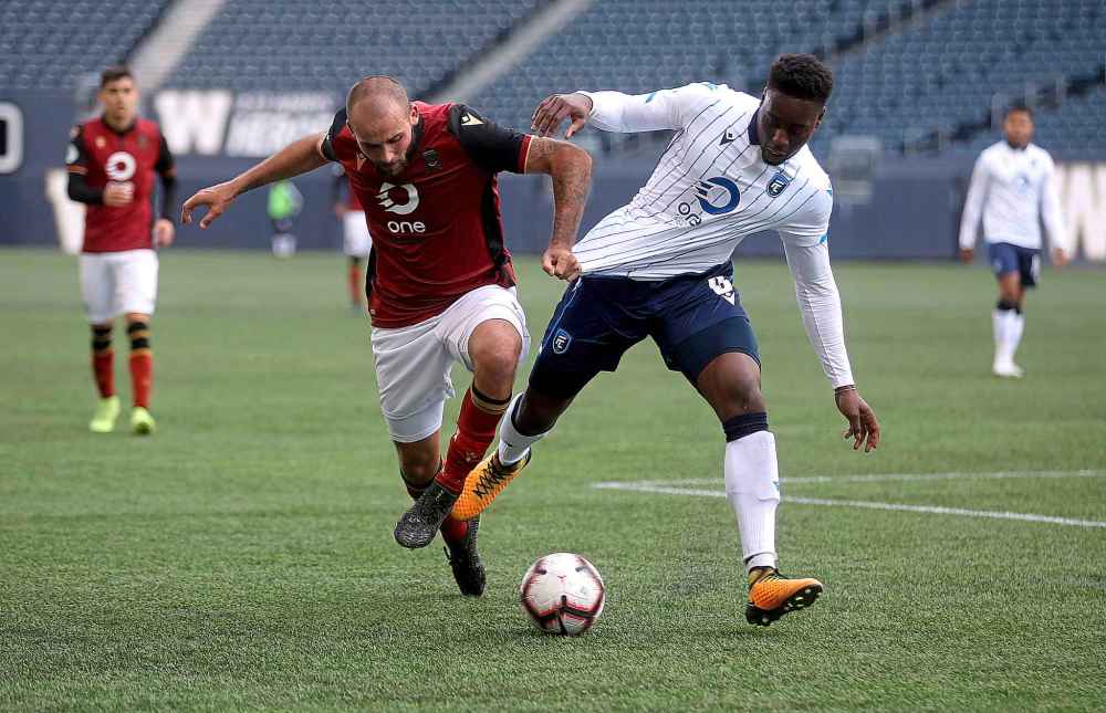 Valour FC's Stephen Hoyle (left) jostles with FC Edmonton's Mele Temguia.