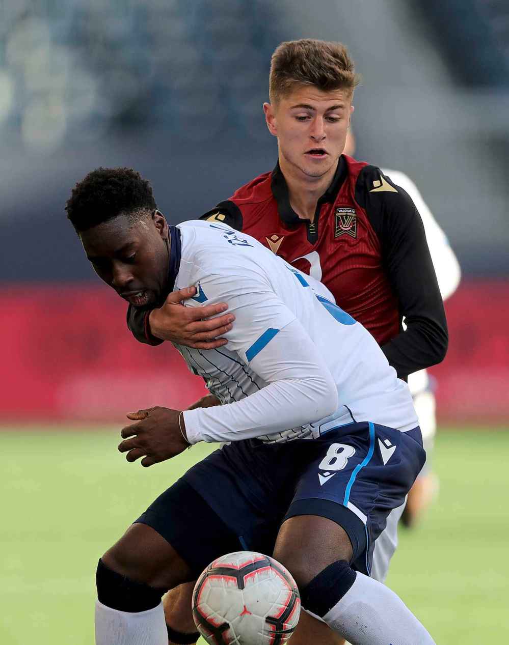 FC Edmonton's Mele Temguia (front) and Valour FC's Tyler Attardo battle for the ball.