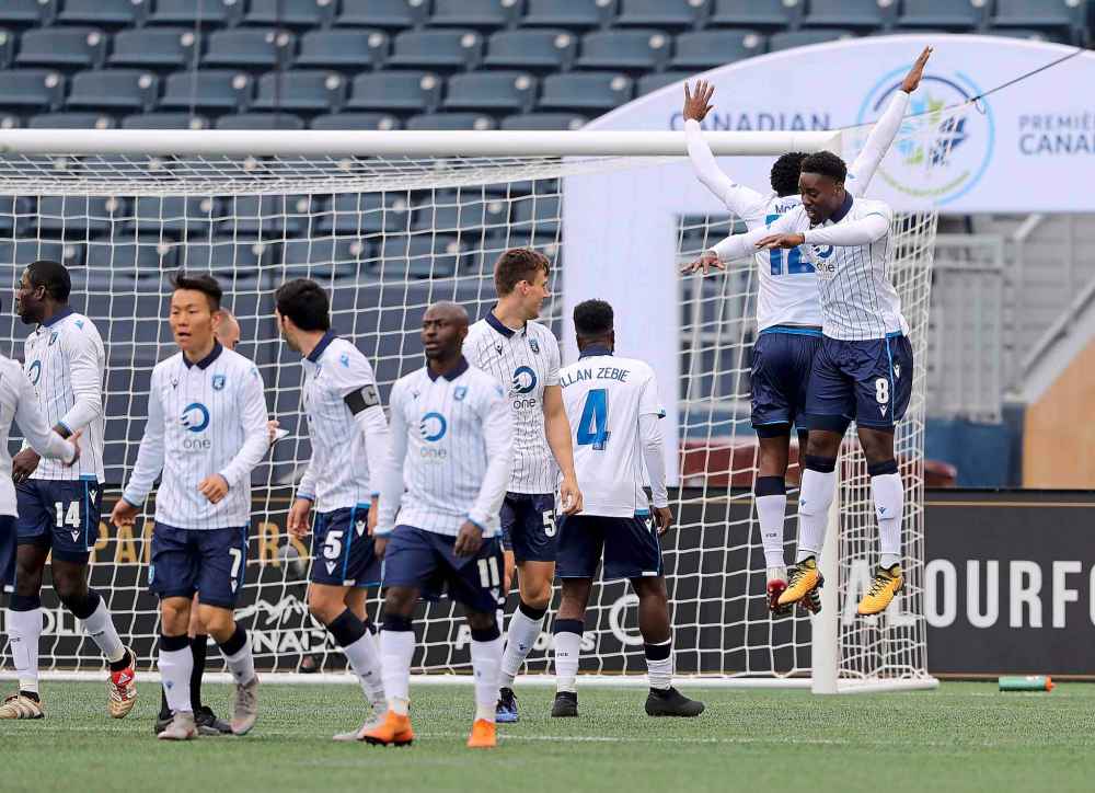 FC Edmonton teammates celebrate after Mele Temguia after he scores.