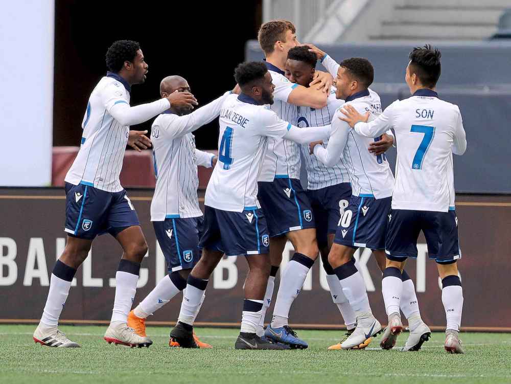 FC Edmonton players celebrate with Mele Temguia after he scores against Valour FC.