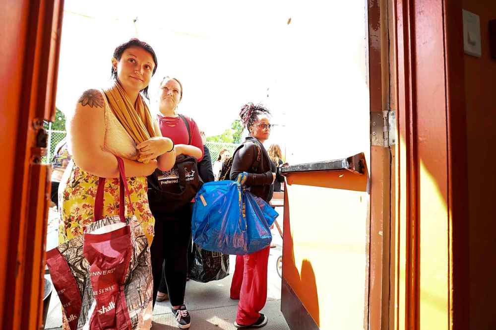 Customers line up outside with their bags waiting their turn to be allowed into market to purchase and pack up their fresh food at the rear of the Indigenous Family Centre.