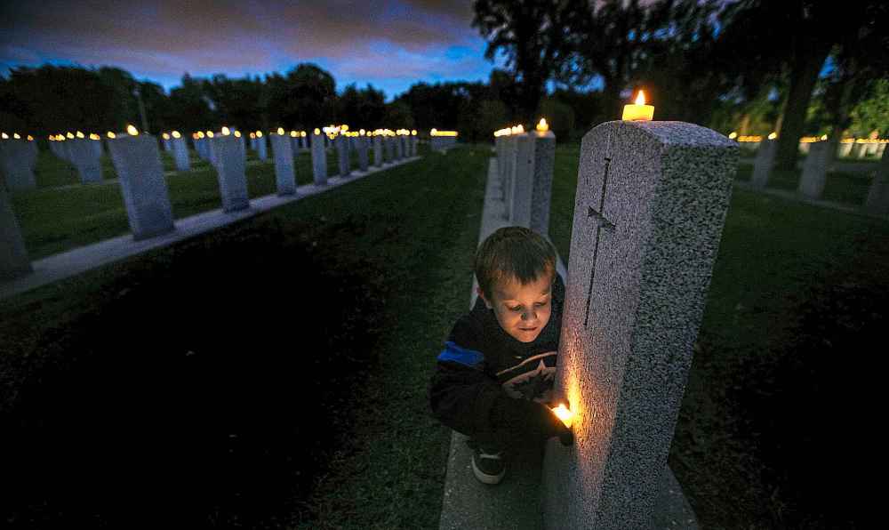 SEPTEMBER 2014: Connor Chaulk checks out names on the rows of veteran graves at Brookside Cemetery at the Candle Light Vigil held to mark the anniversary of the start of World War II.