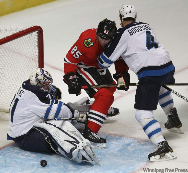 Chicago Blackhawks' Rostislav Olesz, centre, gets pushed into Winnipeg Jets goaltender Ondrej Pavelec by Jets Zach Bogosian during first-period action. (Joe Bryksa / Winnipeg Free Press)