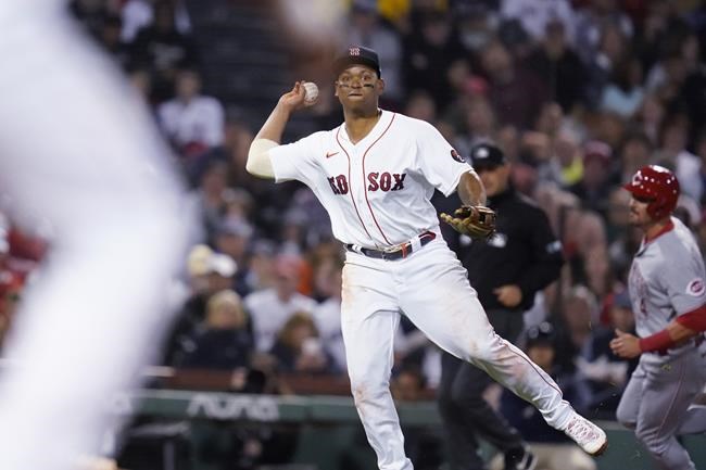 Boston Red Sox third baseman Rafael Devers tries to throw out Cincinnati Reds' Nick Senzel at first on a grounder during the sixth inning of a baseball game Tuesday, May 31, 2022, at Fenway Park in Boston. Devers was charged with a throwing error on the play, which allowed Matt Reynolds, right, to score. (AP Photo/Charles Krupa)