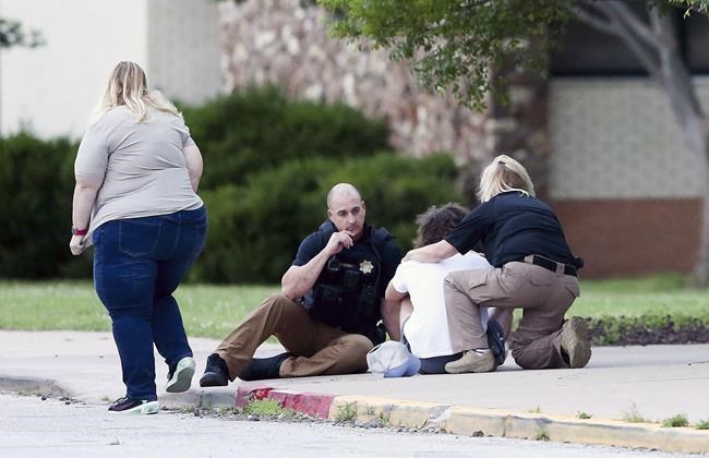 Tulsa Police talk to a young man at Memorial High School as he waits to be reunited with a family member who was evacuated from the scene of a shooting at the Natalie Medical Building Wednesday, June 1, 2022. in Tulsa, Okla. Multiple people were shot at a Tulsa medical building on a hospital campus Wednesday. (Ian Maule/Tulsa World via AP)