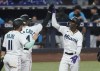 Miami Marlins' Miguel Rojas (11) and Bryan De La Cruz (14) congratulate Jazz Chisholm Jr. after Chisholm hit a grand slam in the second inning of a baseball game against the Washington Nationals, Tuesday, June 7, 2022, in Miami. (AP Photo/Marta Lavandier)