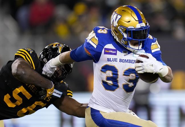 Winnipeg Blue Bombers running back Andrew Harris (33) evades a tackle from Hamilton Tiger-Cats defensive end Ja'Gared Davis (56) during first half football action in the 108th CFL Grey Cup in Hamilton, Ont., on Sunday, December 12, 2021. THE CANADIAN PRESS/Nathan Denette