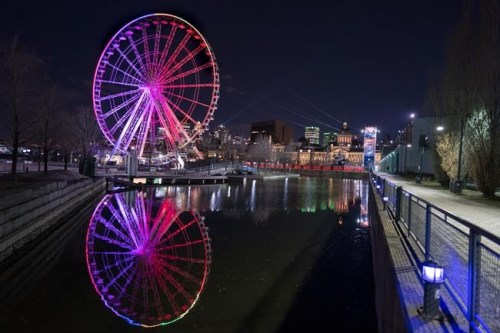 The ferris wheel is lit to the colours of the rainbow, in Montreal, on Monday, April 6, 2020. Quebec's workplace safety board says deficient safety practices at a ferris wheel in Montreal's Old Port led to the death of a worker on Christmas Day 2021. THE CANADIAN PRESS/Paul Chiasson