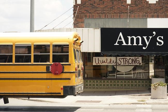 A school bus passes a 'Uvalde Strong' sign placed in the window of a business to honor the victims killed in the recent school shooting at Robb Elementary, Thursday, June 9, 2022, in Uvalde, Texas. The Texas elementary school where a gunman killed 19 children and two teachers has long been a part of the fabric of the small city of Uvalde, a school attended by generations of families, and where the spark came that led to Hispanic parents and students to band together to fight discrimination over a half-century ago. (AP Photo/Eric Gay)