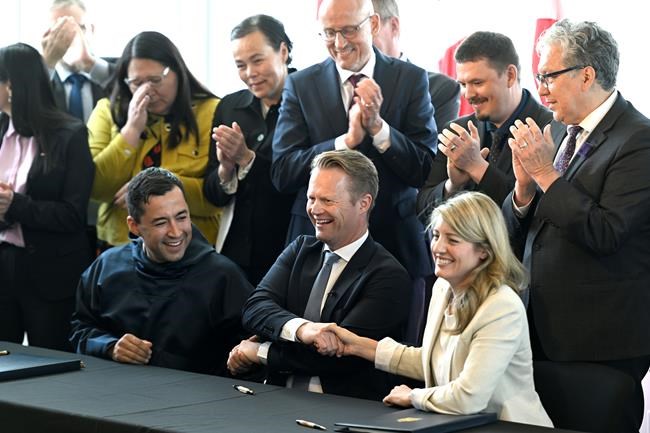 Prime Minister of Greenland Mute Bourup Egede, Minister for Foreign Affairs of the Kingdom of Denmark Jeppe Kofod, centre, and Canada’s Minister of Foreign Affairs Melanie Joly share a three-way handshake after signing an agreement that will establish a land border between Canada and the Kingdom of Denmark on Hans Island, an Arctic island between Nunavut and Greenland, in Ottawa, on Tuesday, June 14, 2022. THE CANADIAN PRESS/Justin Tang